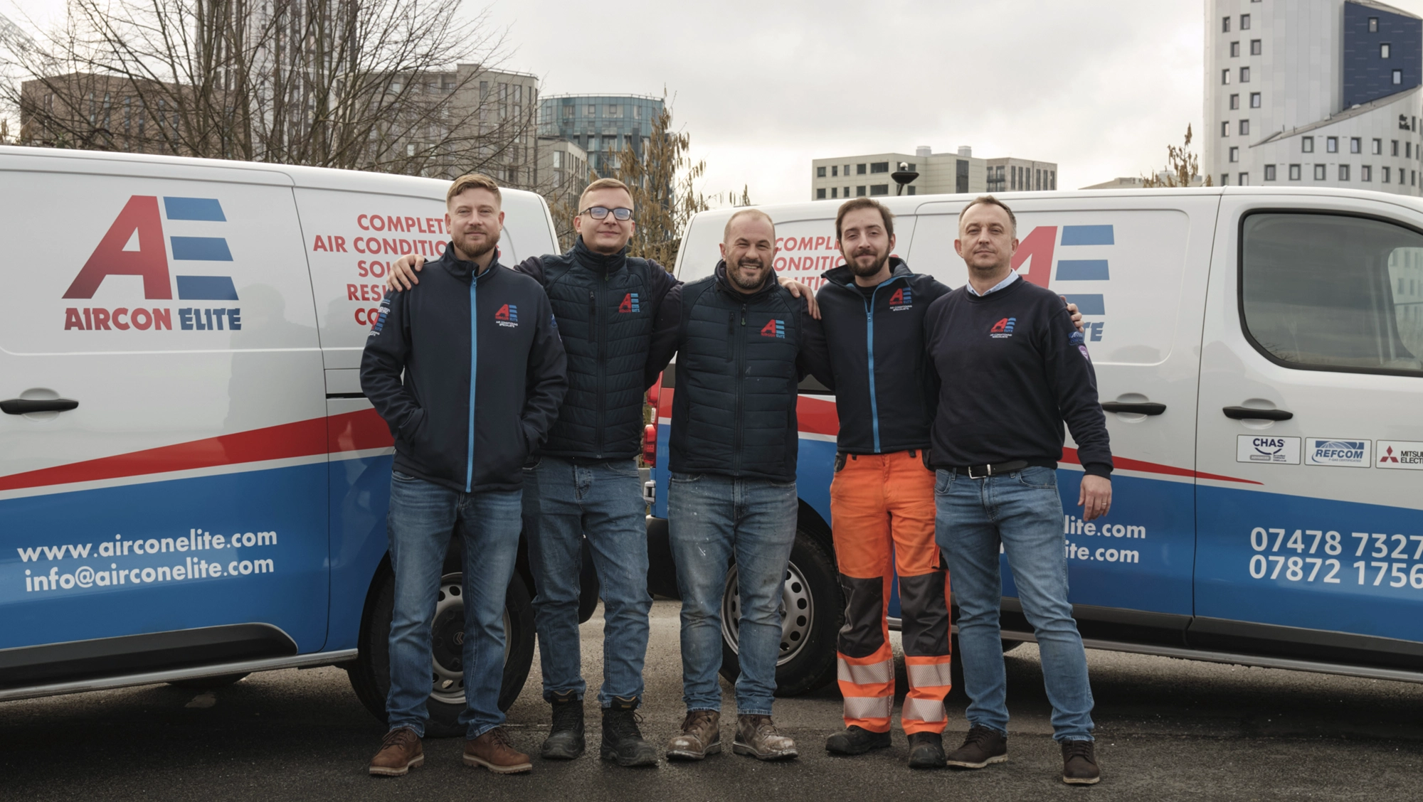 The Aircon Elite team standing together in front of company vans