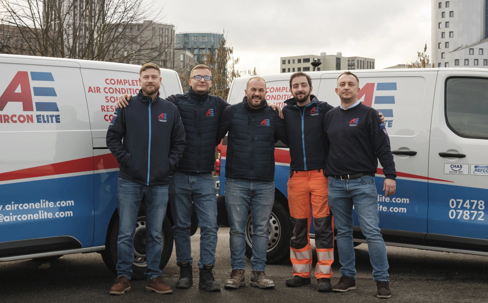 The Aircon Elite team standing together in front of company vans